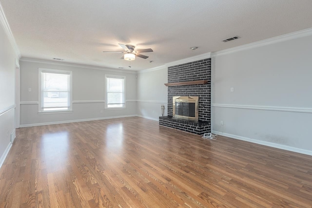 unfurnished living room with visible vents, a fireplace, crown molding, and wood finished floors