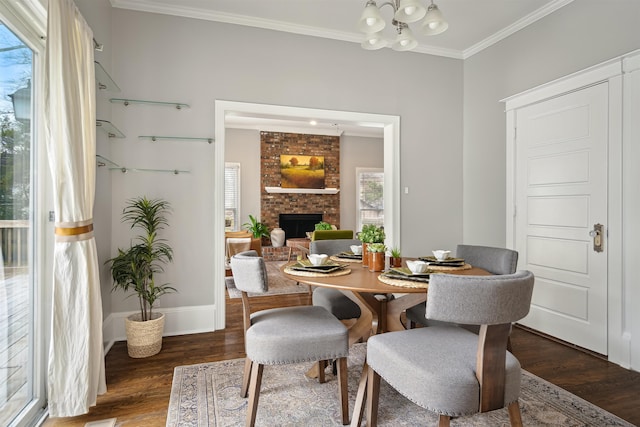 dining space with an inviting chandelier, dark wood-type flooring, a brick fireplace, and crown molding