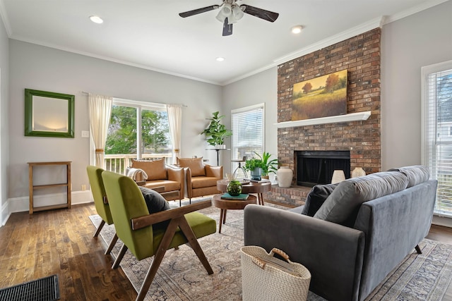 living area with crown molding, a brick fireplace, wood finished floors, and baseboards