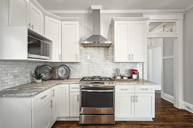 kitchen featuring appliances with stainless steel finishes, white cabinetry, crown molding, and wall chimney range hood