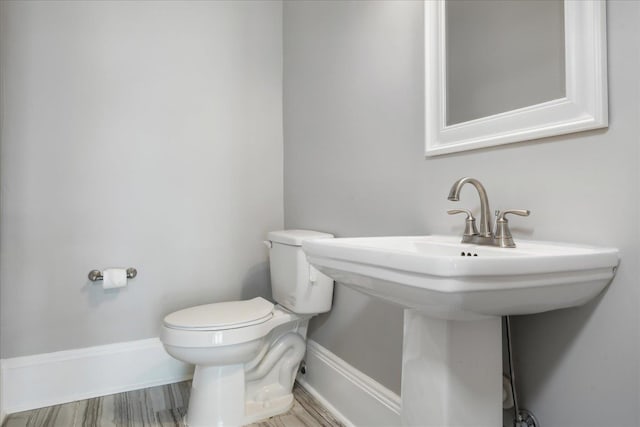 bathroom featuring toilet, baseboards, and a sink