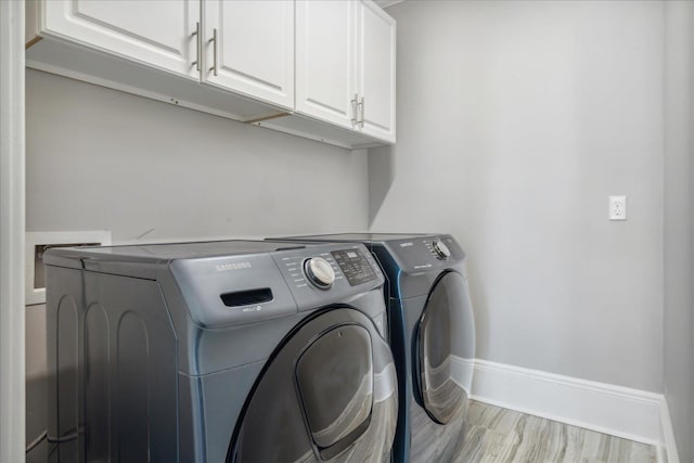 washroom with washer and dryer, baseboards, and cabinet space