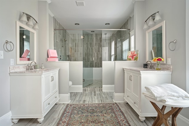 full bath featuring a shower stall, two vanities, visible vents, and a sink