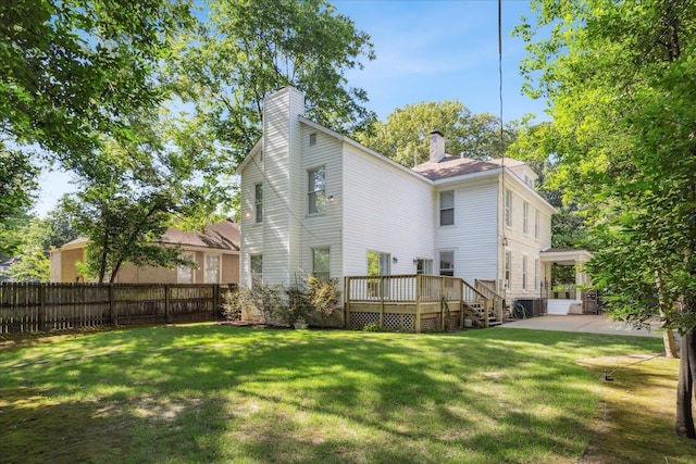 back of property featuring a patio, fence, a chimney, a deck, and a lawn