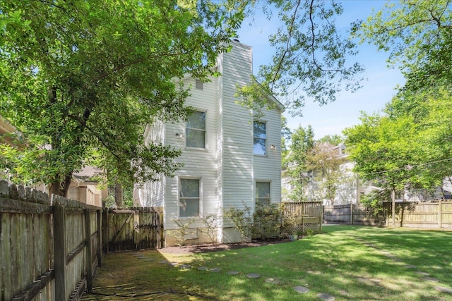 rear view of house with a fenced backyard, a wooden deck, a chimney, and a yard