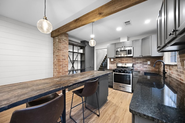 kitchen with visible vents, beam ceiling, gray cabinetry, a sink, and appliances with stainless steel finishes