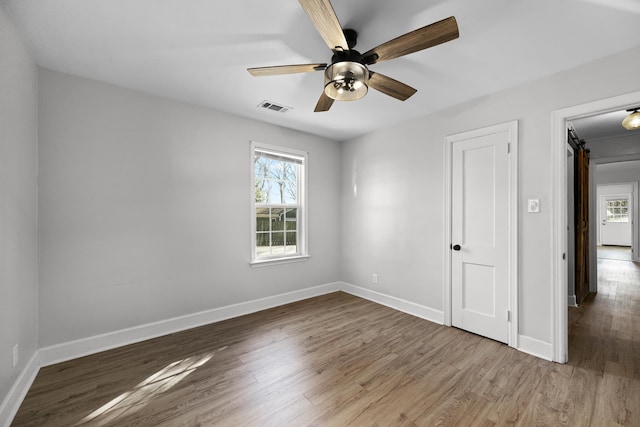 spare room featuring ceiling fan, wood finished floors, visible vents, and baseboards