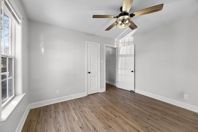 unfurnished room with baseboards, wood finished floors, and a ceiling fan