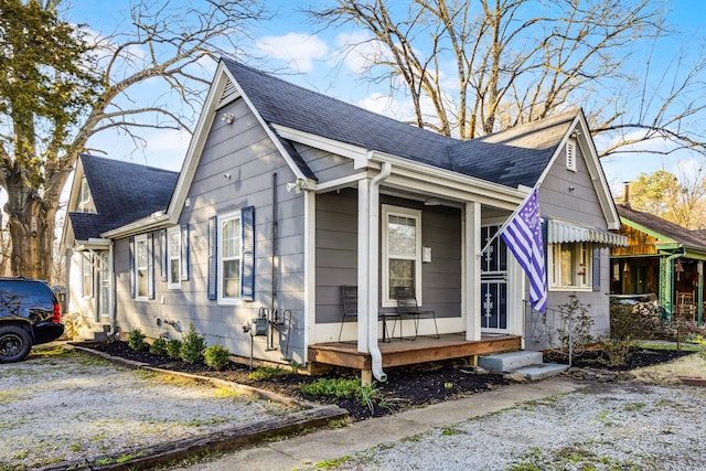 view of home's exterior with gravel driveway, a porch, and roof with shingles