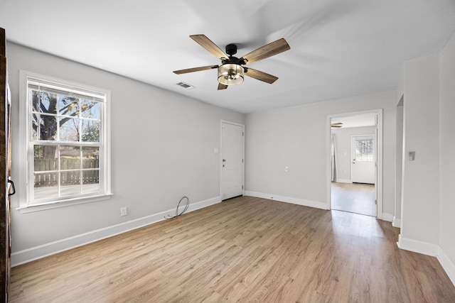 empty room featuring visible vents, a ceiling fan, baseboards, and wood finished floors