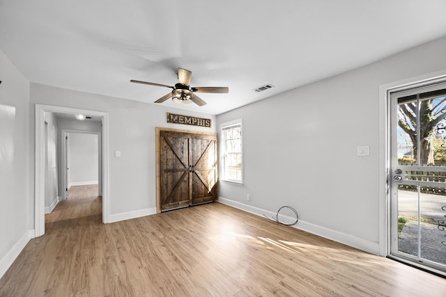 empty room featuring ceiling fan, visible vents, baseboards, and wood finished floors