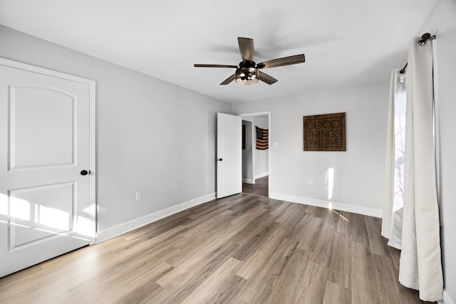 unfurnished bedroom featuring wood finished floors, baseboards, and ceiling fan