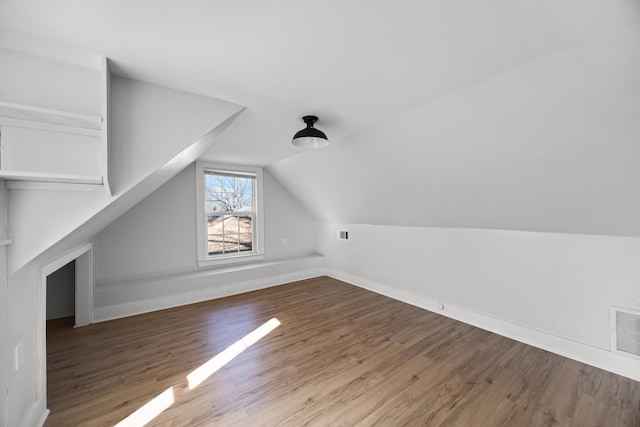 bonus room featuring vaulted ceiling, baseboards, visible vents, and wood finished floors