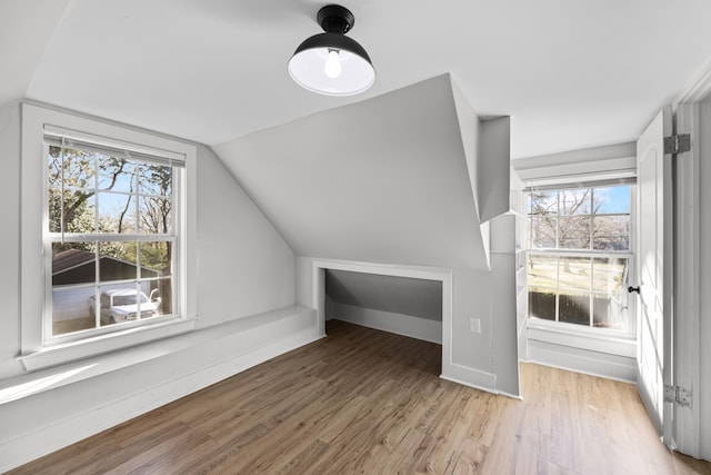 additional living space featuring vaulted ceiling, light wood-style floors, and baseboards