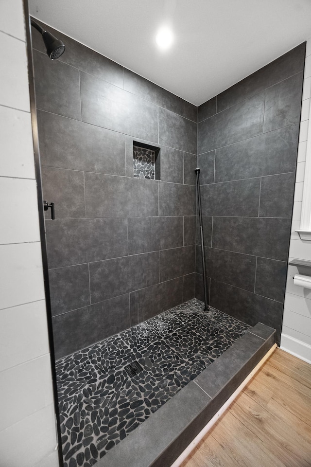 full bathroom with wood finished floors and a tile shower