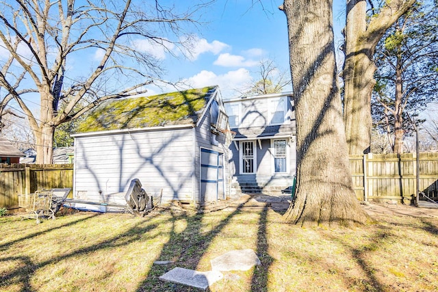 rear view of house featuring solar panels, a yard, and fence