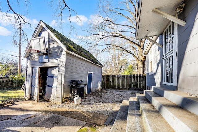 view of home's exterior with a garage, entry steps, an outdoor structure, and fence