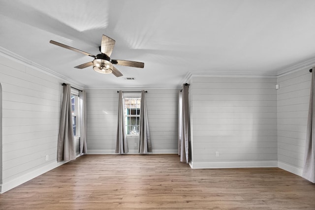 empty room featuring visible vents, a ceiling fan, light wood-style floors, crown molding, and baseboards