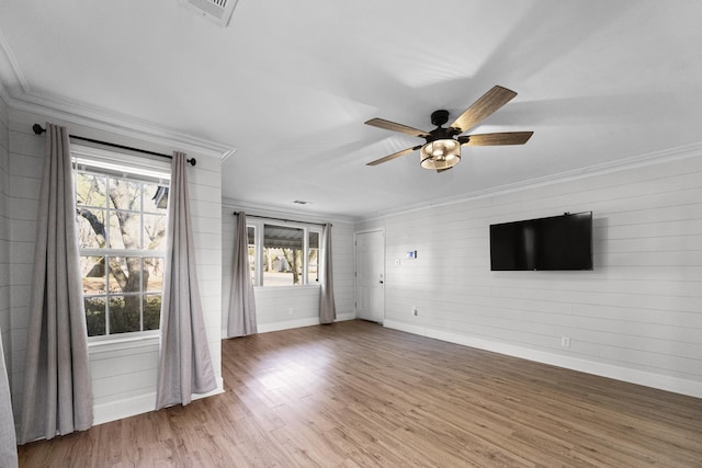 unfurnished living room featuring visible vents, ornamental molding, wood finished floors, baseboards, and ceiling fan