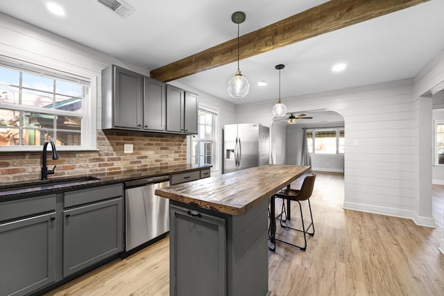 kitchen featuring visible vents, arched walkways, a sink, butcher block countertops, and stainless steel appliances