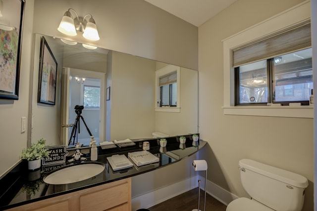 bathroom with baseboards, a chandelier, toilet, wood finished floors, and vanity