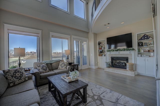 living room with visible vents, plenty of natural light, wood finished floors, and a tile fireplace