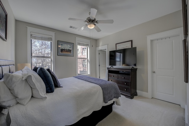 bedroom with ceiling fan, light colored carpet, visible vents, and baseboards