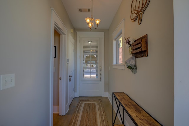 doorway to outside with a chandelier, light wood-style floors, and baseboards