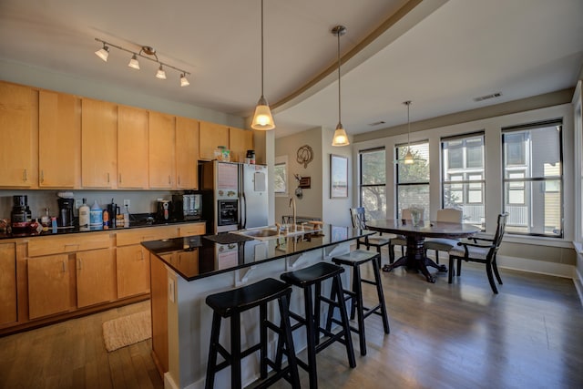 kitchen featuring dark countertops, visible vents, refrigerator with ice dispenser, plenty of natural light, and a sink