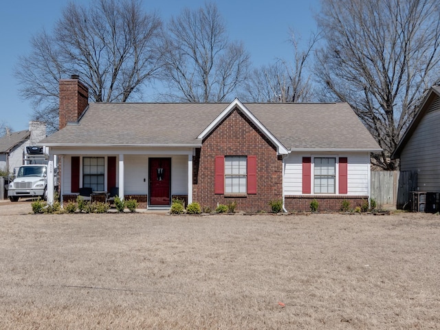 ranch-style house featuring a porch, fence, a shingled roof, brick siding, and a chimney