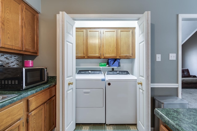 clothes washing area with washing machine and clothes dryer and cabinet space