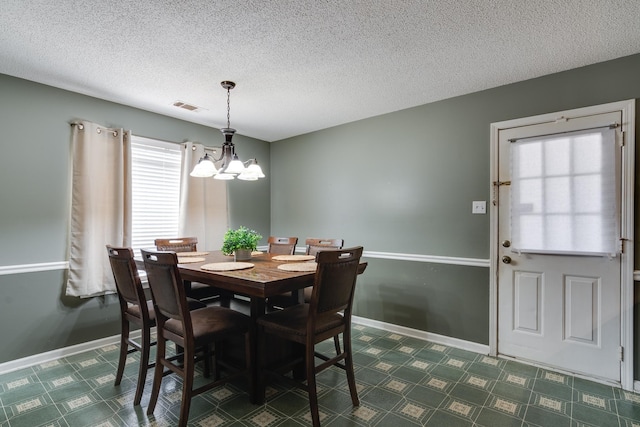 dining room featuring baseboards, visible vents, a textured ceiling, dark floors, and a chandelier