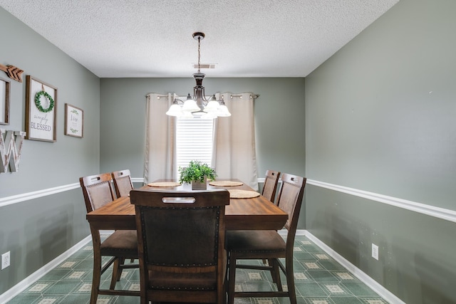 dining space featuring visible vents, baseboards, a textured ceiling, and a chandelier