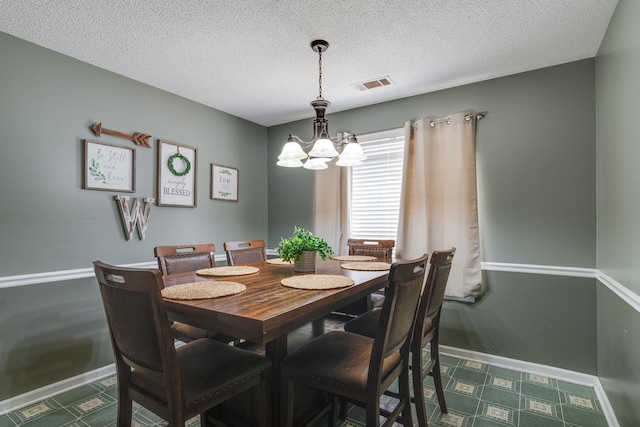 dining room with visible vents, baseboards, a textured ceiling, and a notable chandelier