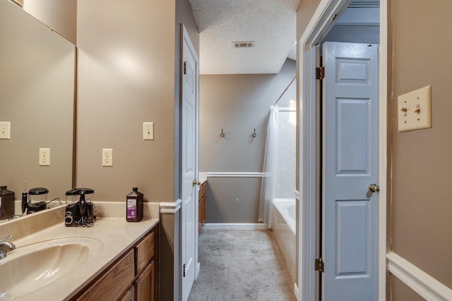 full bathroom featuring visible vents, shower / tub combo, a textured ceiling, and vanity