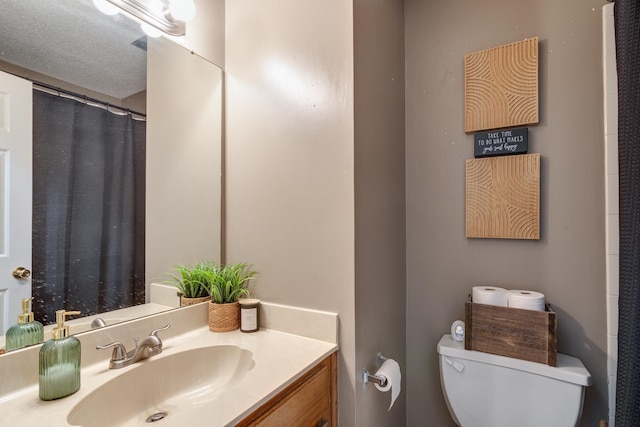 bathroom featuring vanity, a shower with shower curtain, toilet, and a textured ceiling