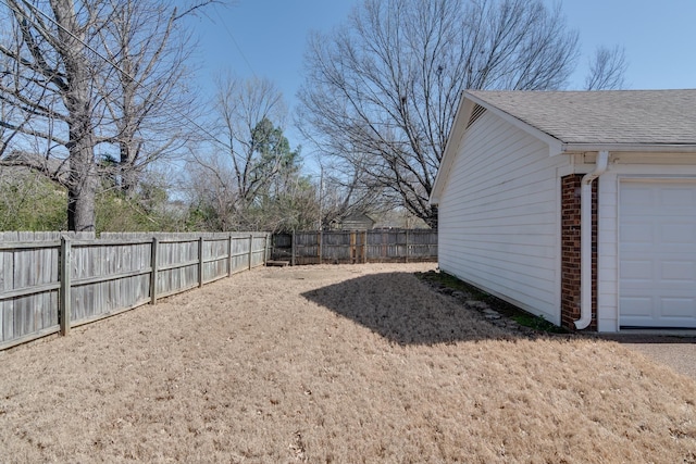 view of yard featuring a garage and a fenced backyard