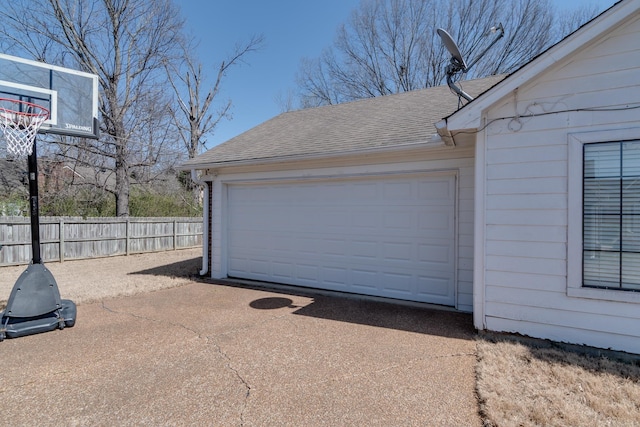 garage featuring driveway and fence