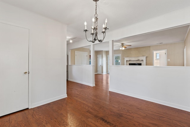 unfurnished room with ceiling fan with notable chandelier, wood finished floors, crown molding, a fireplace, and baseboards