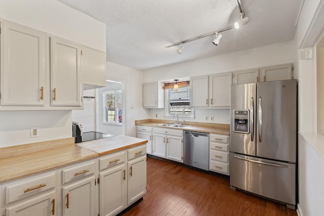 kitchen with dark wood finished floors, a sink, light countertops, appliances with stainless steel finishes, and a textured ceiling