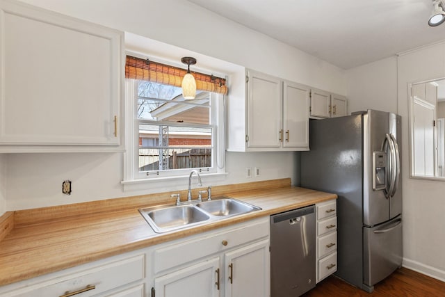 kitchen featuring dark wood finished floors, white cabinets, appliances with stainless steel finishes, and a sink