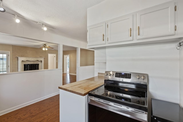 kitchen featuring dark wood-style floors, a textured ceiling, stainless steel electric range, and white cabinets