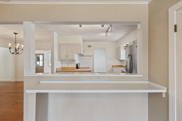 kitchen with visible vents, wood finished floors, an inviting chandelier, stainless steel fridge with ice dispenser, and light countertops