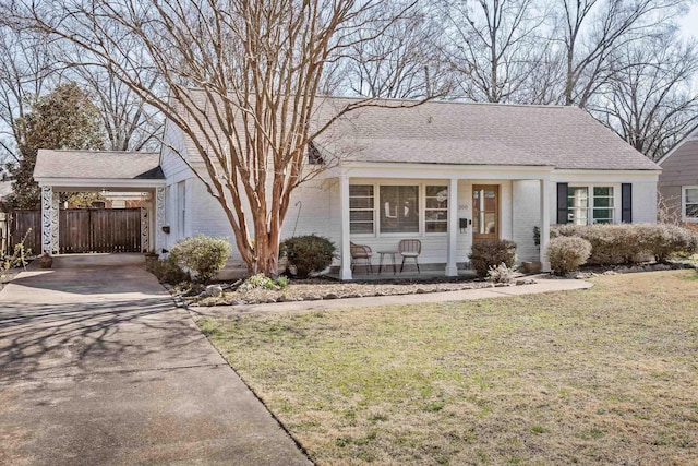 view of front of house with a front yard, fence, concrete driveway, a carport, and brick siding