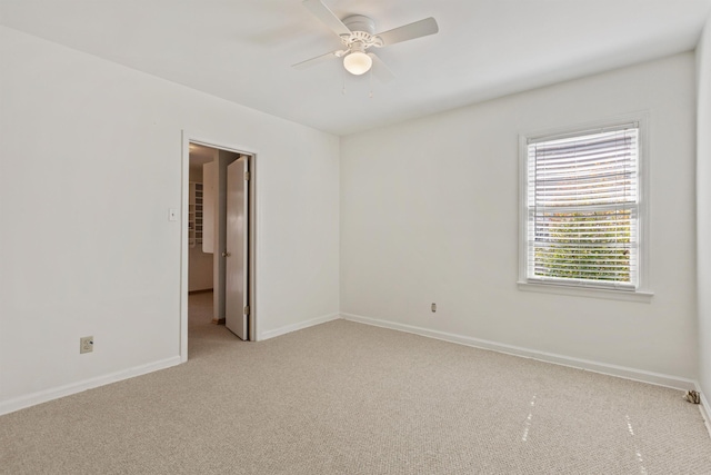 unfurnished room featuring light carpet, a ceiling fan, and baseboards