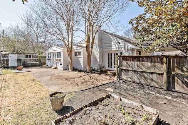 back of property featuring brick siding, a patio, french doors, and fence