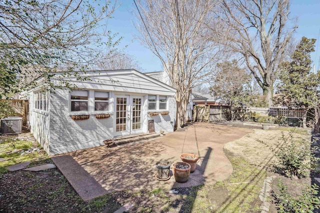 exterior space featuring brick siding, cooling unit, french doors, and a fenced backyard