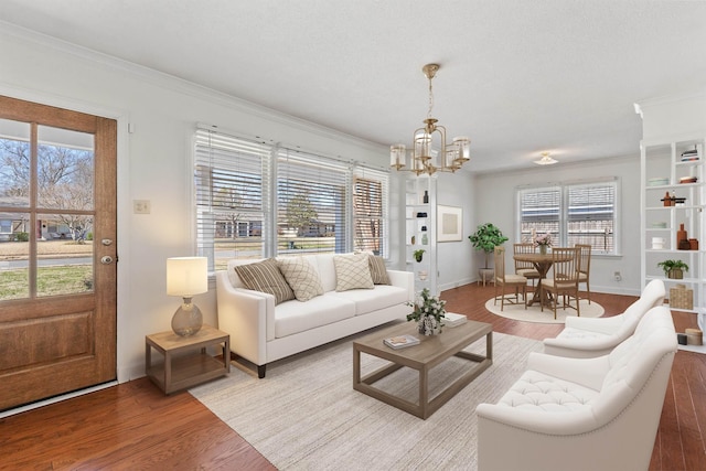 living room featuring crown molding, a notable chandelier, wood finished floors, and baseboards