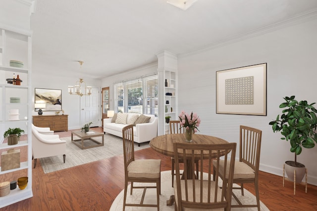 dining room featuring baseboards, a notable chandelier, wood finished floors, and ornamental molding