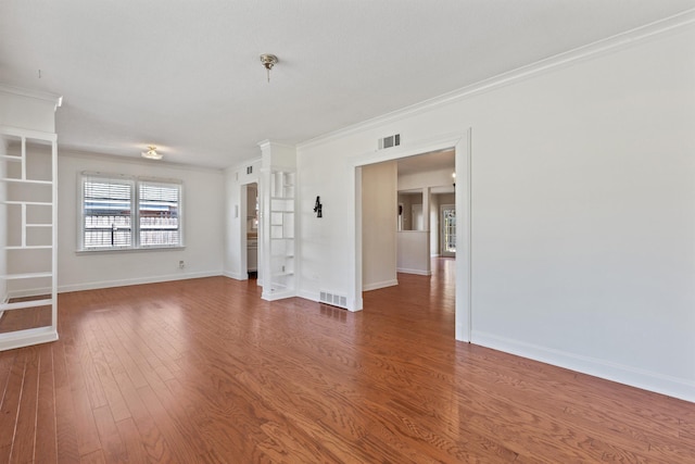 unfurnished room featuring crown molding, wood finished floors, visible vents, and baseboards